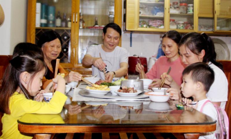 Hình ảnh một gia đình Việt Nam nhiều thế hệ quây quần bên mâm cơm, thể hiện sự ấm cúng, gắn kết và truyền thống